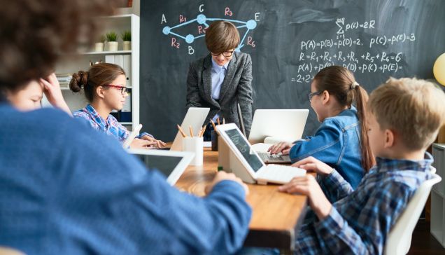 Klasa lekcyjna, w której uczniowie korzystając z laptopów uczą się nowych rzeczy