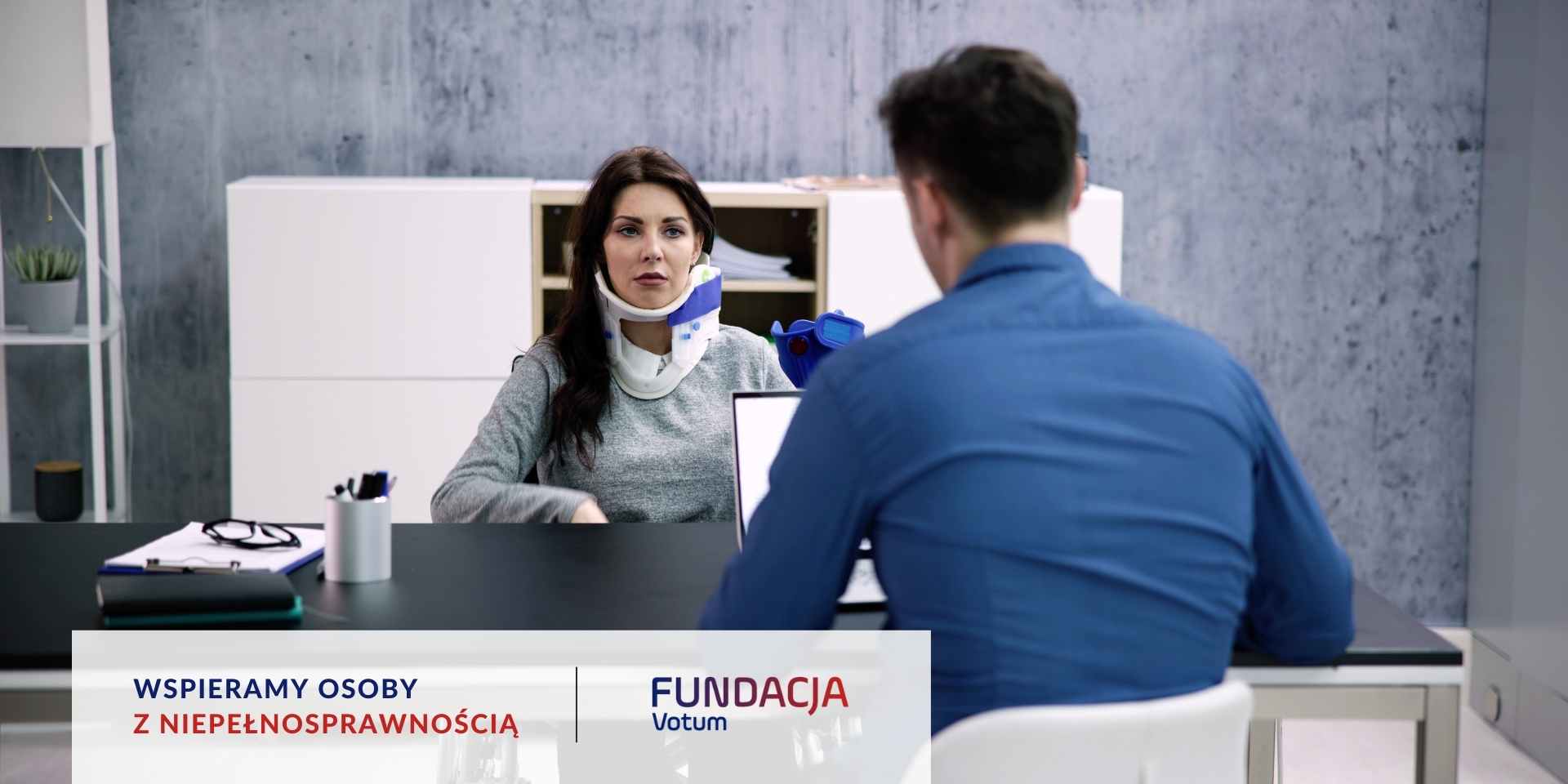 
Kobieta z ortezą na szyi siedzi przy biurku i rozmawia z prawnikiem.
